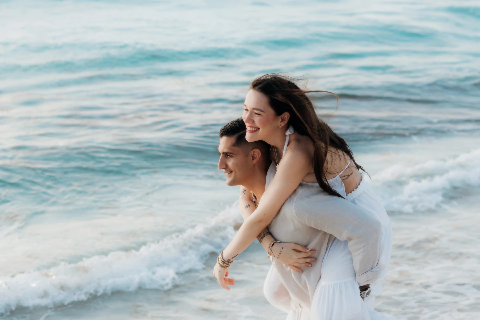 Couple piggyback on the beach in Puerto Morelos