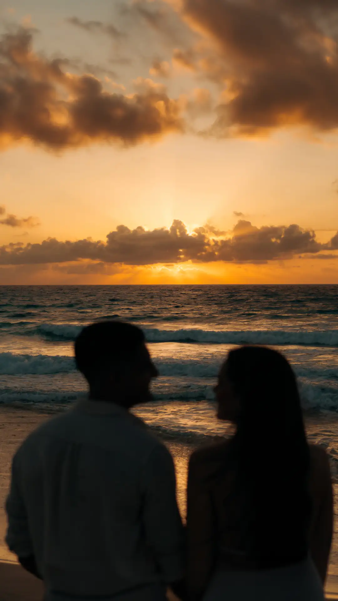 Couple in silhouette watching the sunset on the beach, Cancún