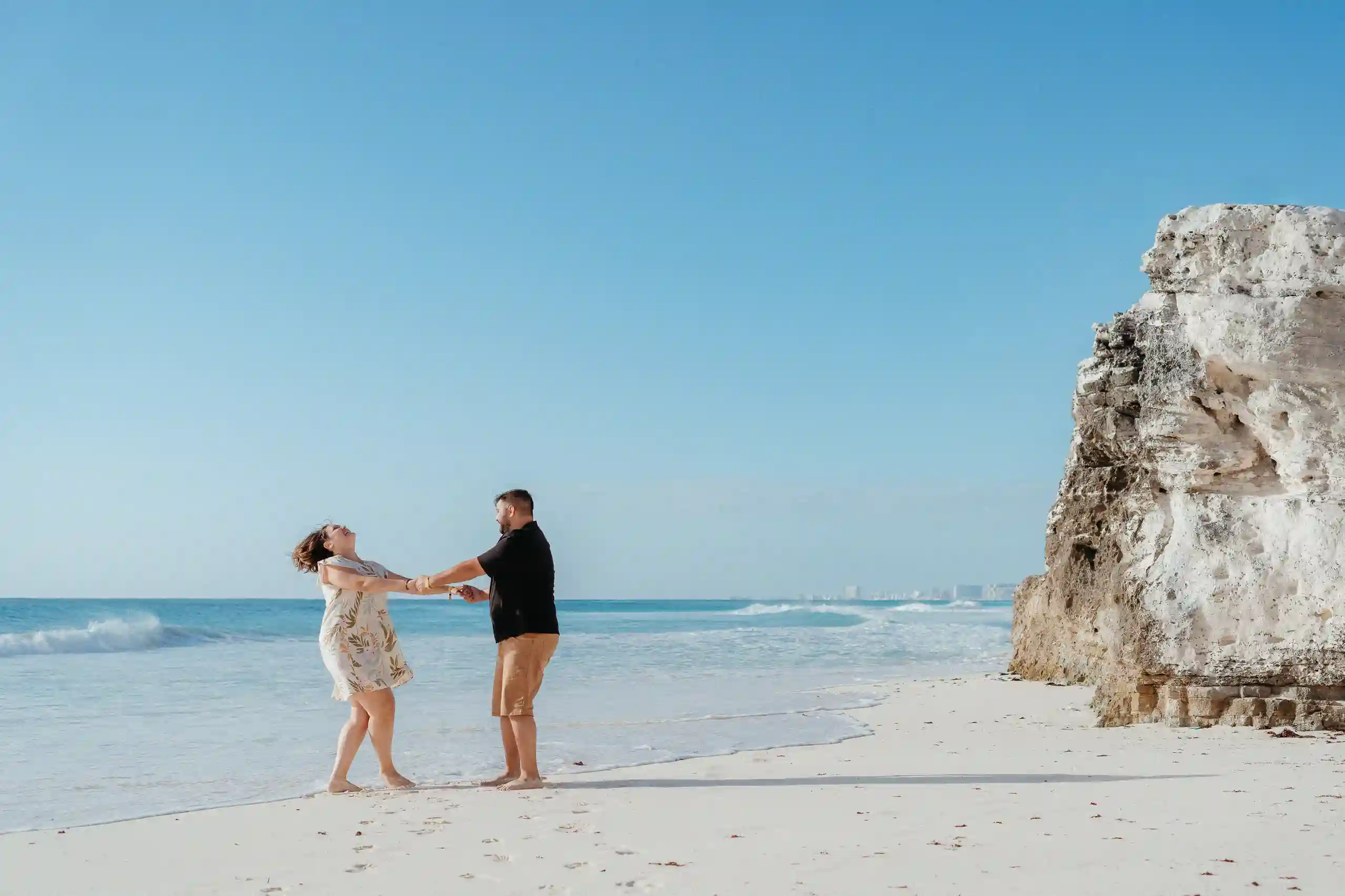 Couple holding hands and laughing on a quiet white-sand Caribbean beach