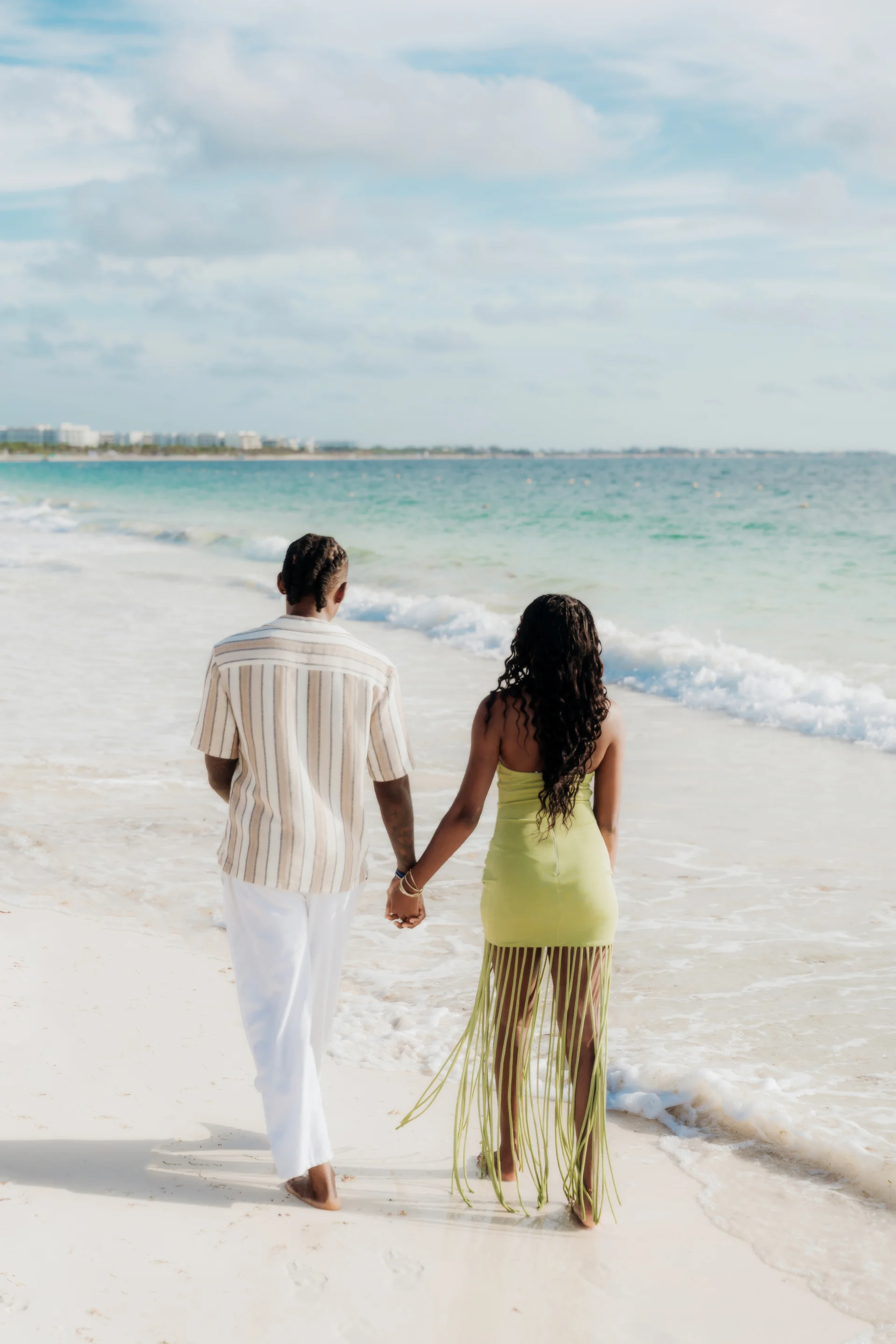 Couple viewed from behind holding hands and gazing out at the turquoise sea, RIU Latino, Costa Mujeres
