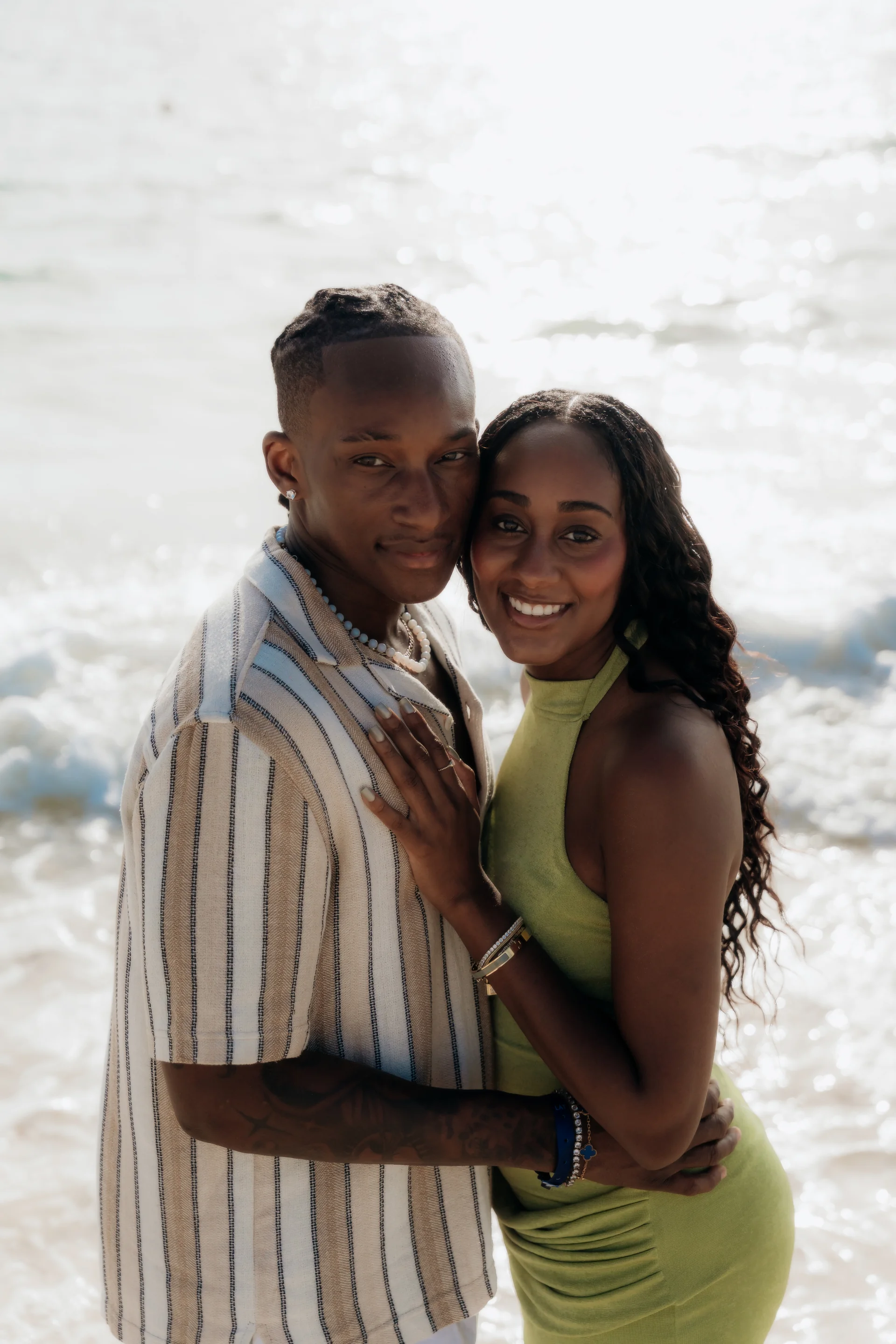 Couple embracing cheek to cheek and smiling at the camera in front of the surf, RIU Latino, Costa Mujeres