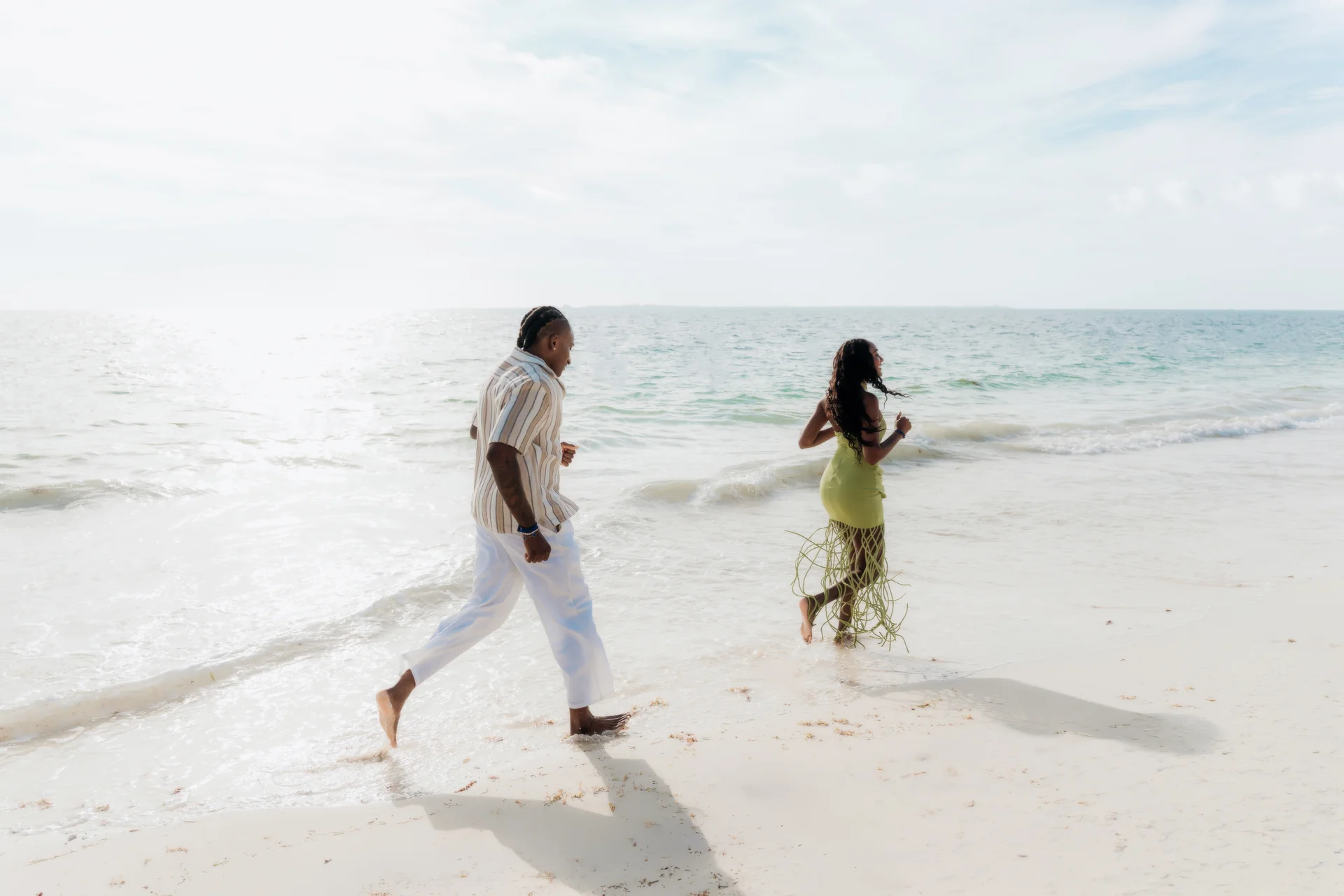 Couple running playfully through the shallow water along the shoreline, RIU Latino, Costa Mujeres