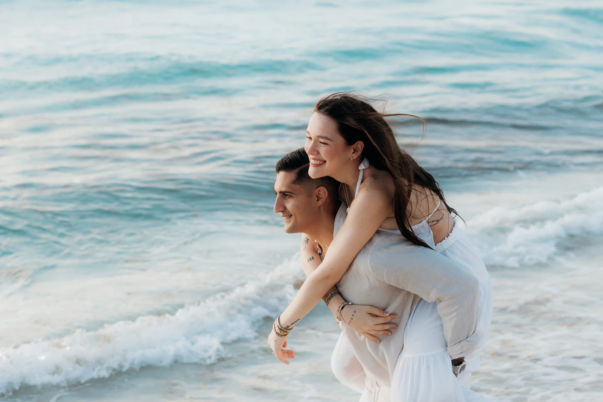 Couple standing wrapped together by the sea, Playa Delfines, Cancún