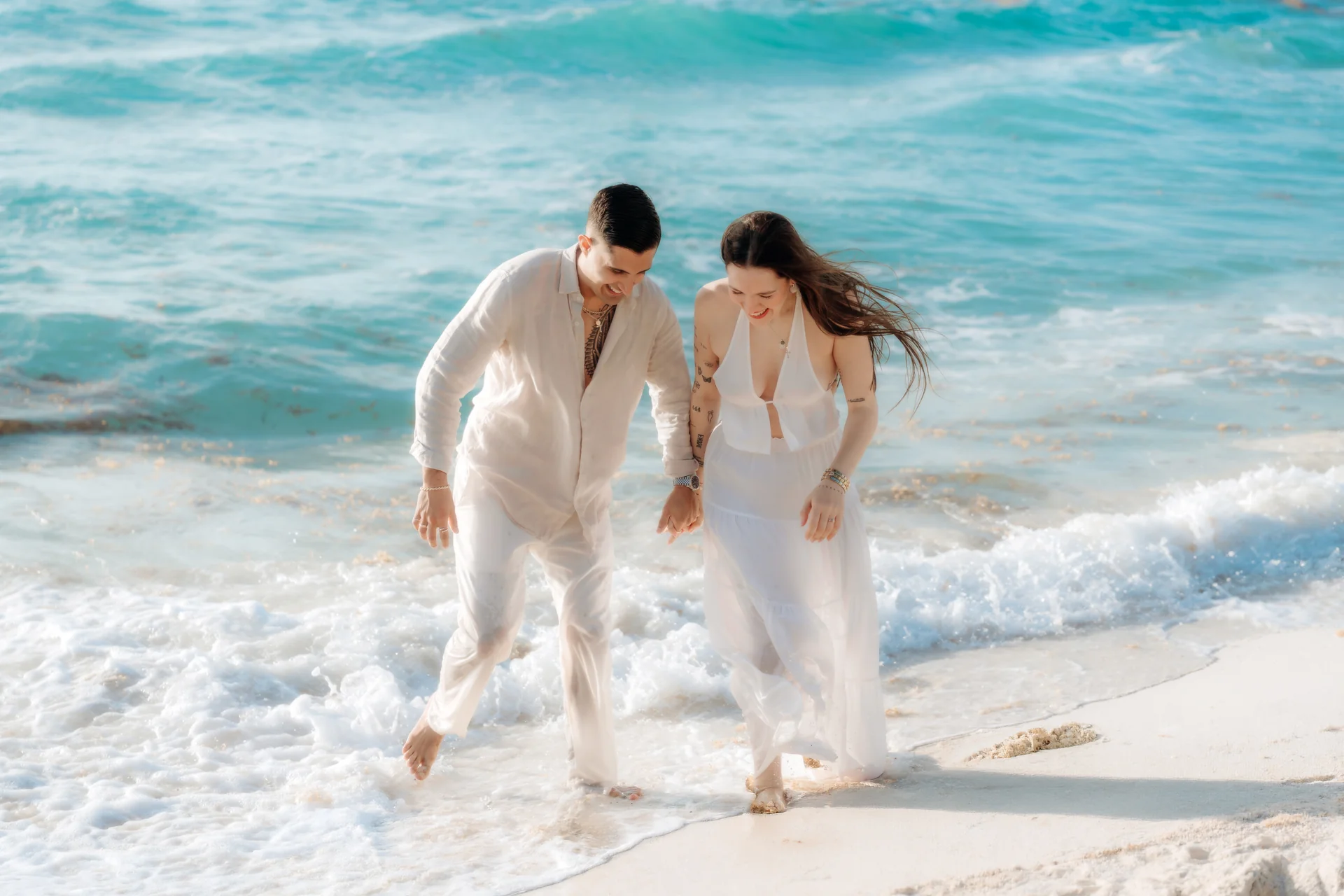 Couple sitting close at the water's edge, Playa Delfines, Cancún