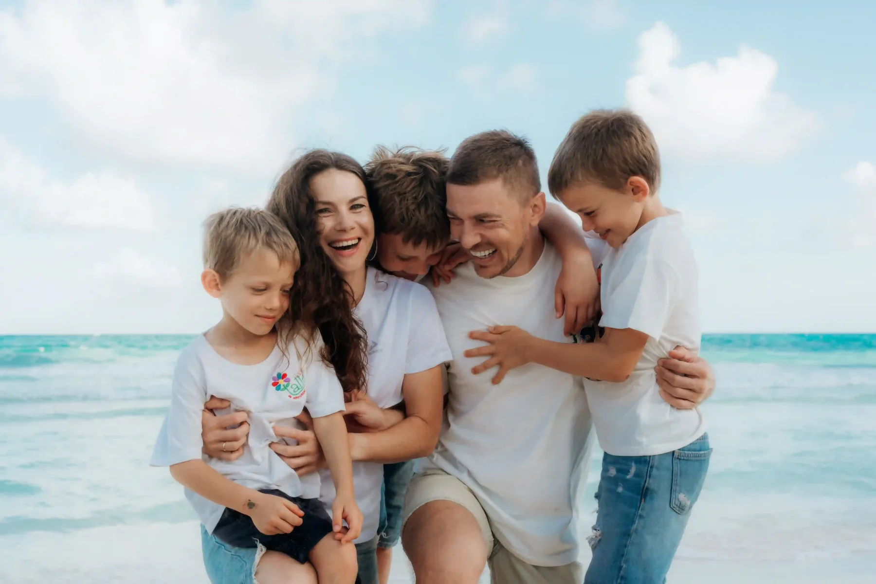 Family running and laughing together on Cancún beach during golden hour family photoshoot