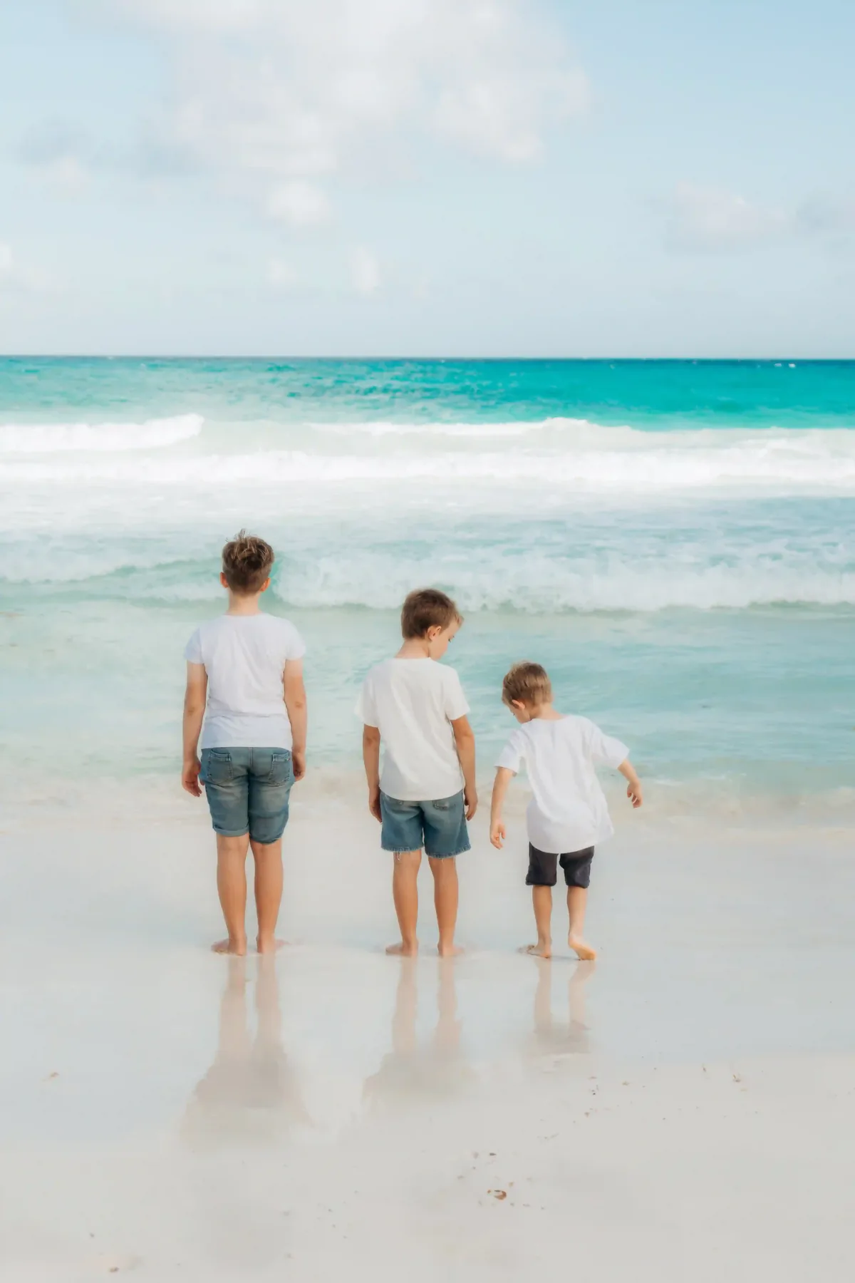 Siblings playing together at the water's edge during family photoshoot in Cancún