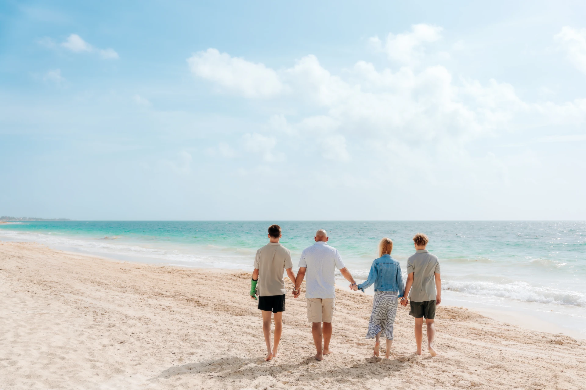 Family of four seen from behind looking out at the Caribbean Sea in Cancún.