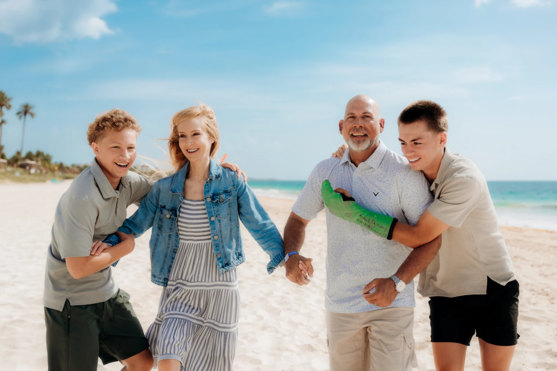 Family of four hugging and laughing together on the beach in Cancún.
