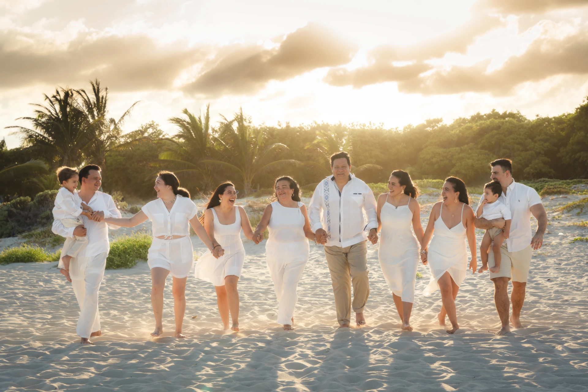 Family walking on a Cancún beach in warm evening light during a golden-hour session