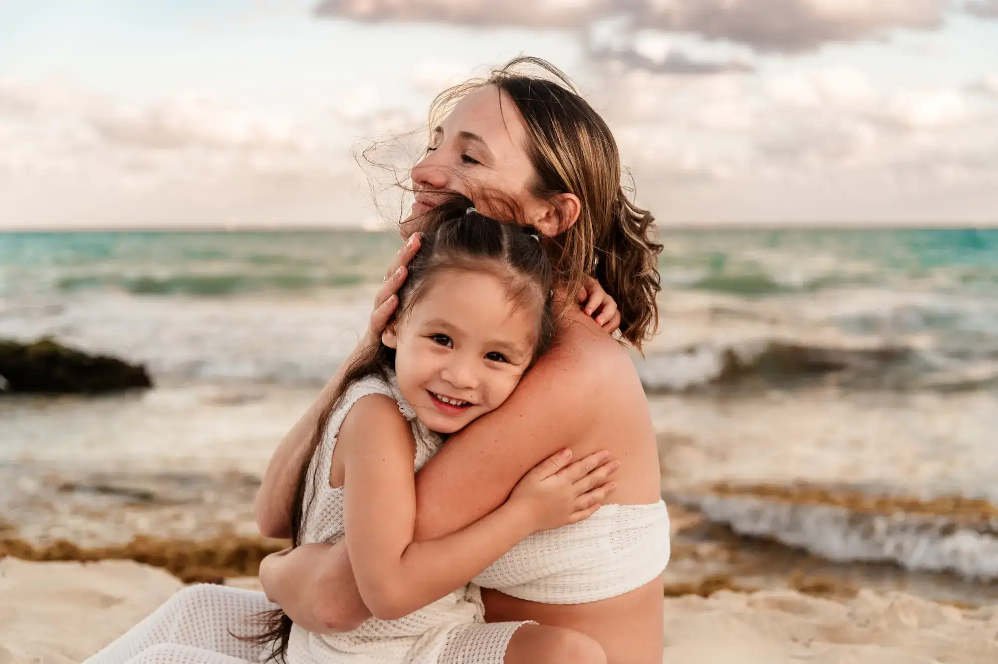 Mother and daughter embracing on the beach in the Riviera Maya