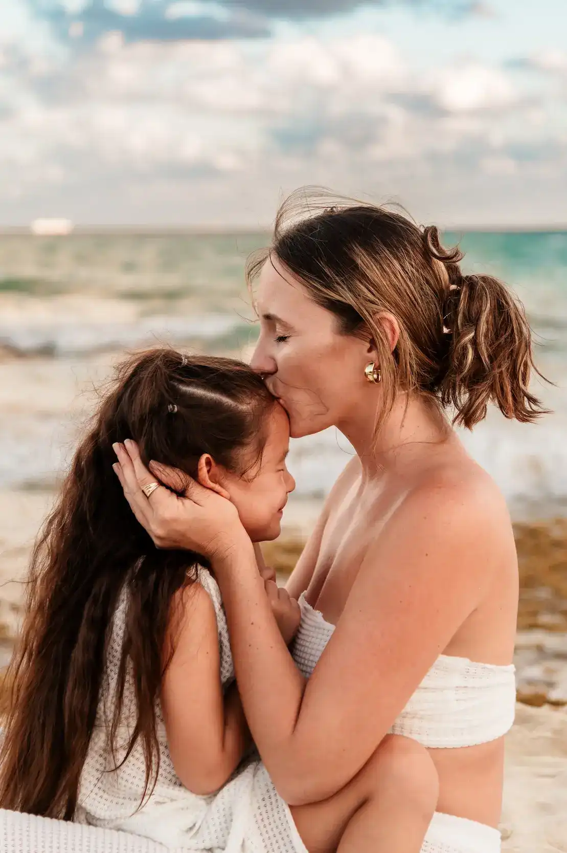 Mother and daughter walking along the water at golden hour, Playa del Carmen
