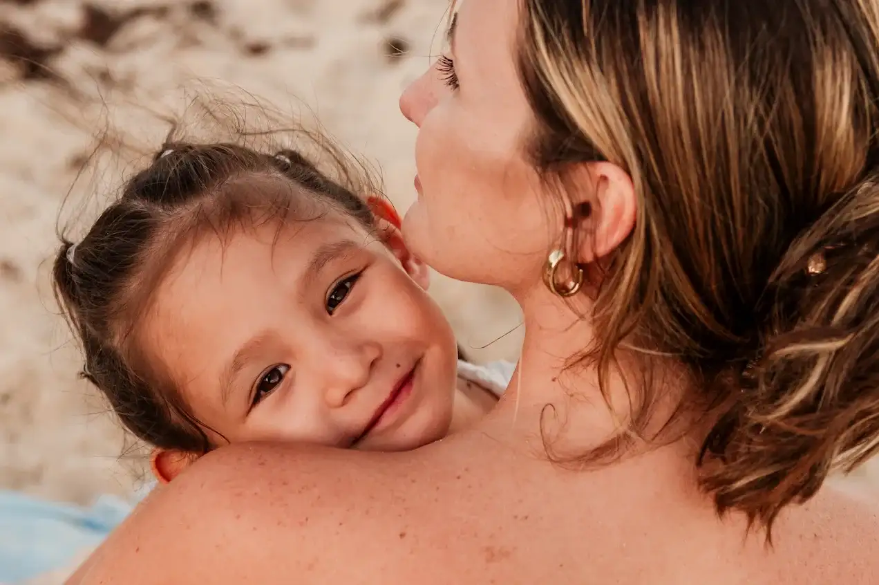 Daughter resting on her mother's shoulder on the beach, Playa del Carmen