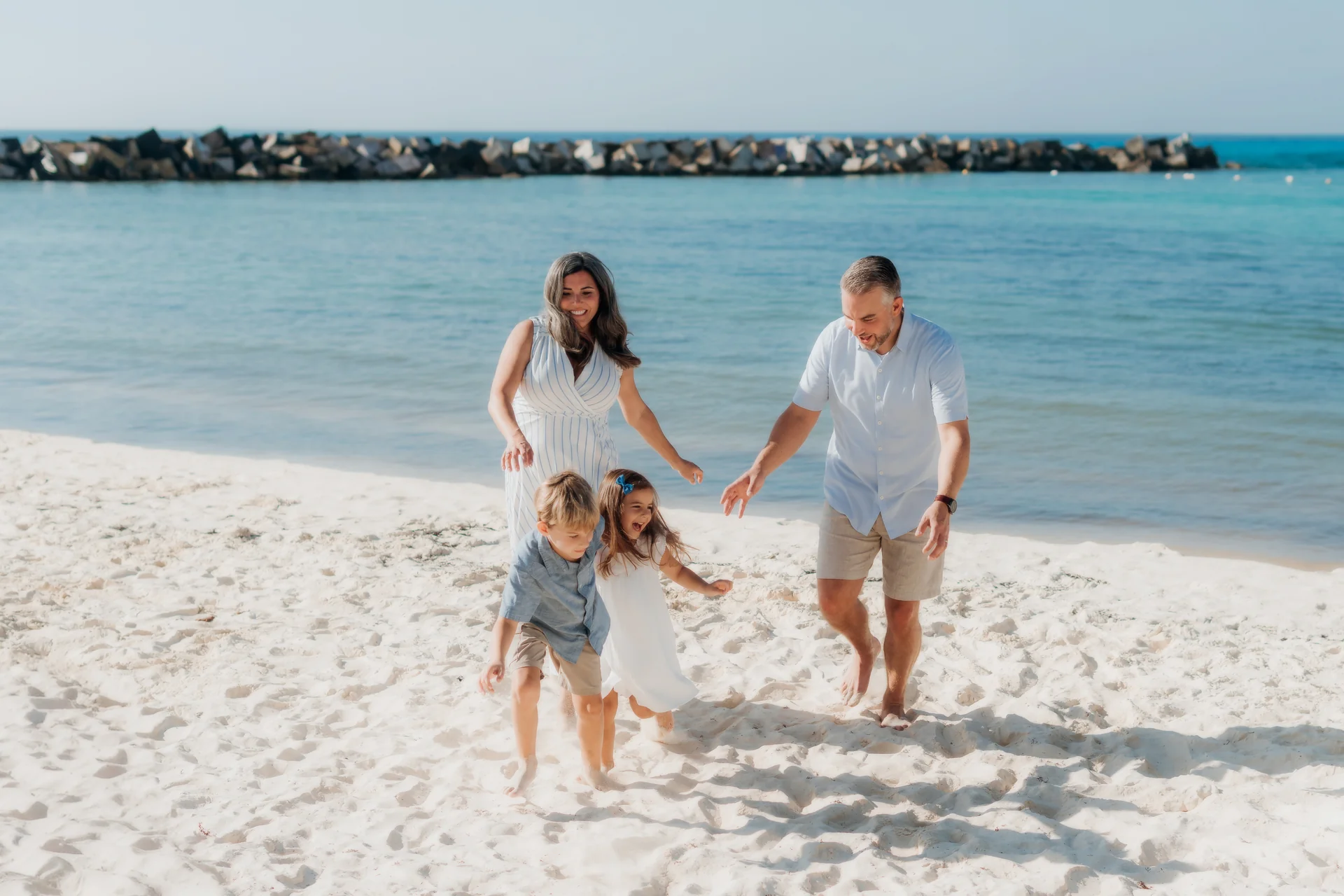Family of four walking together toward the camera on the beach, Hyatt Ziva, Cancún