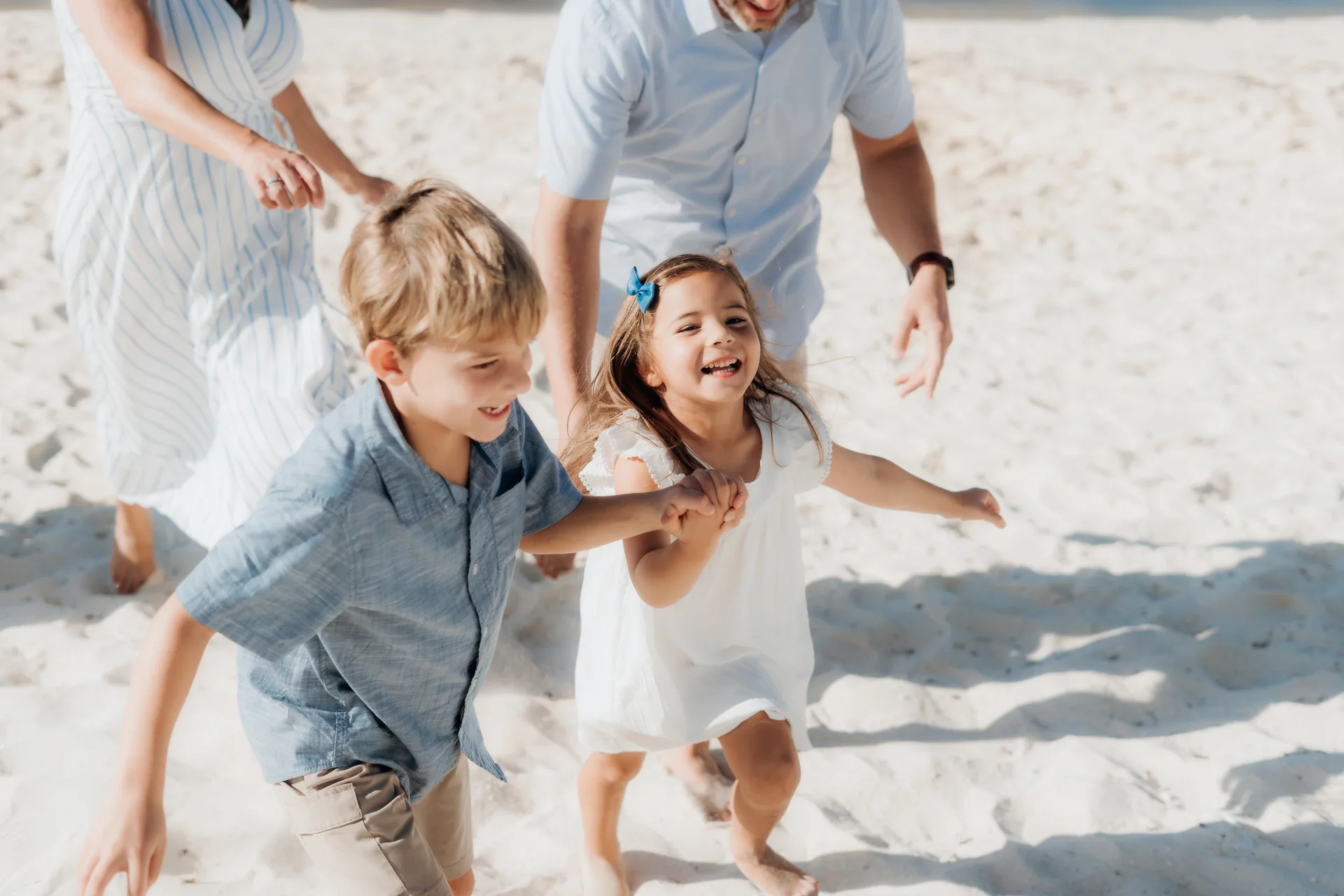 Boy and girl holding hands and laughing as they run across the sand ahead of their parents, Hyatt Ziva, Cancún