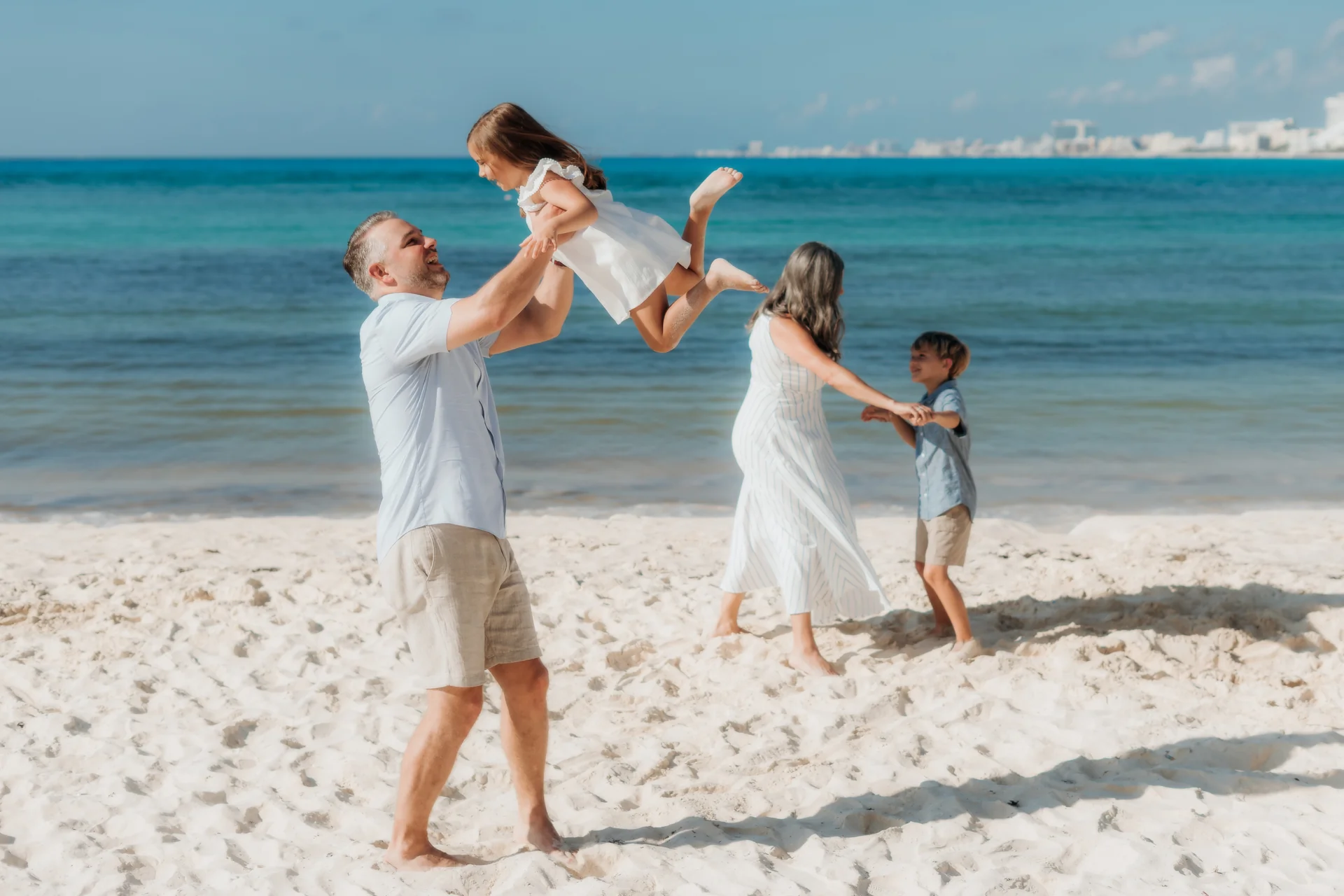 Father lifting his daughter into the air while mother swings her son by the water, Hyatt Ziva, Cancún