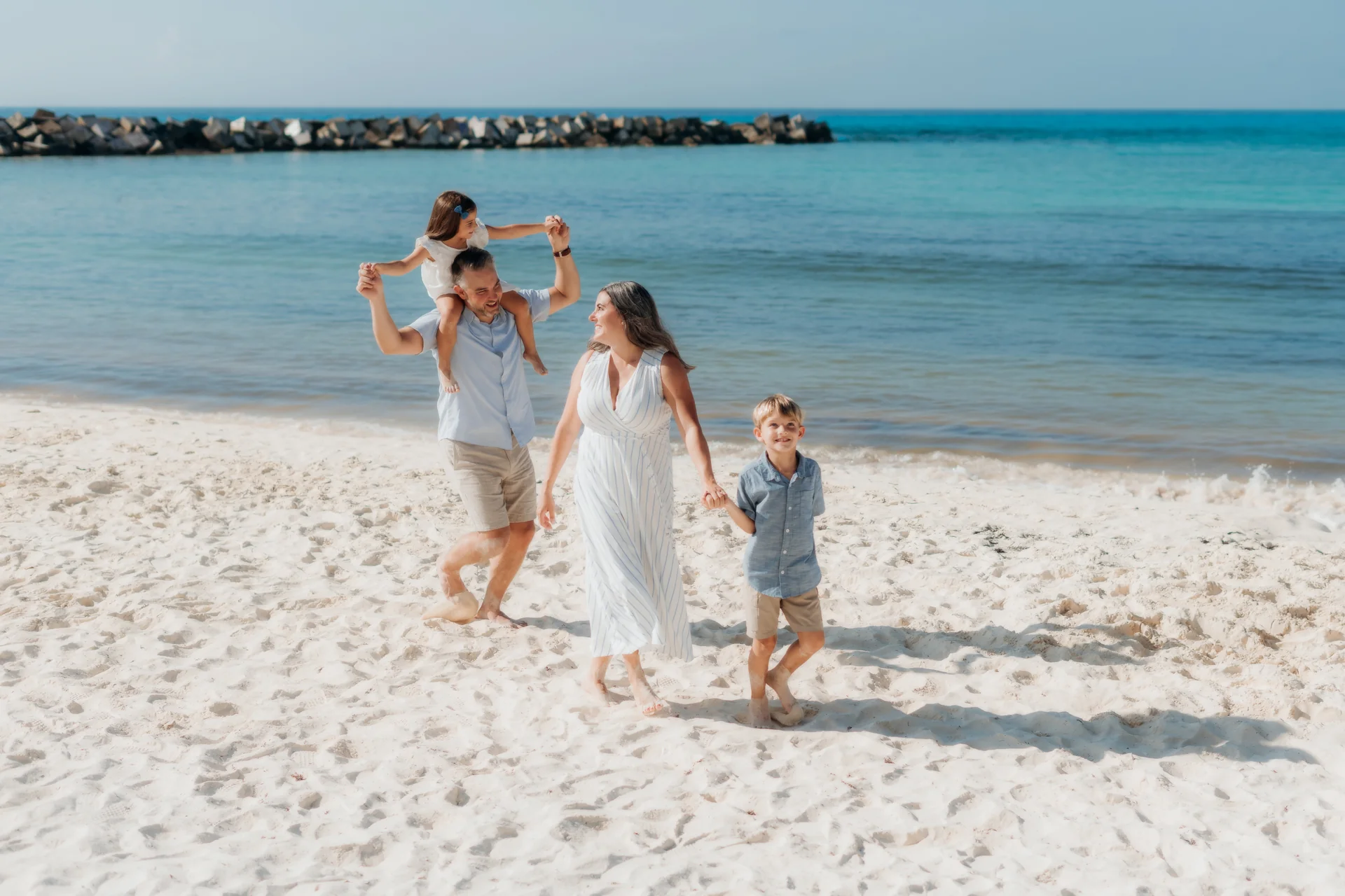 Parents lifting their toddler at the water's edge, Hyatt Ziva, Cancún