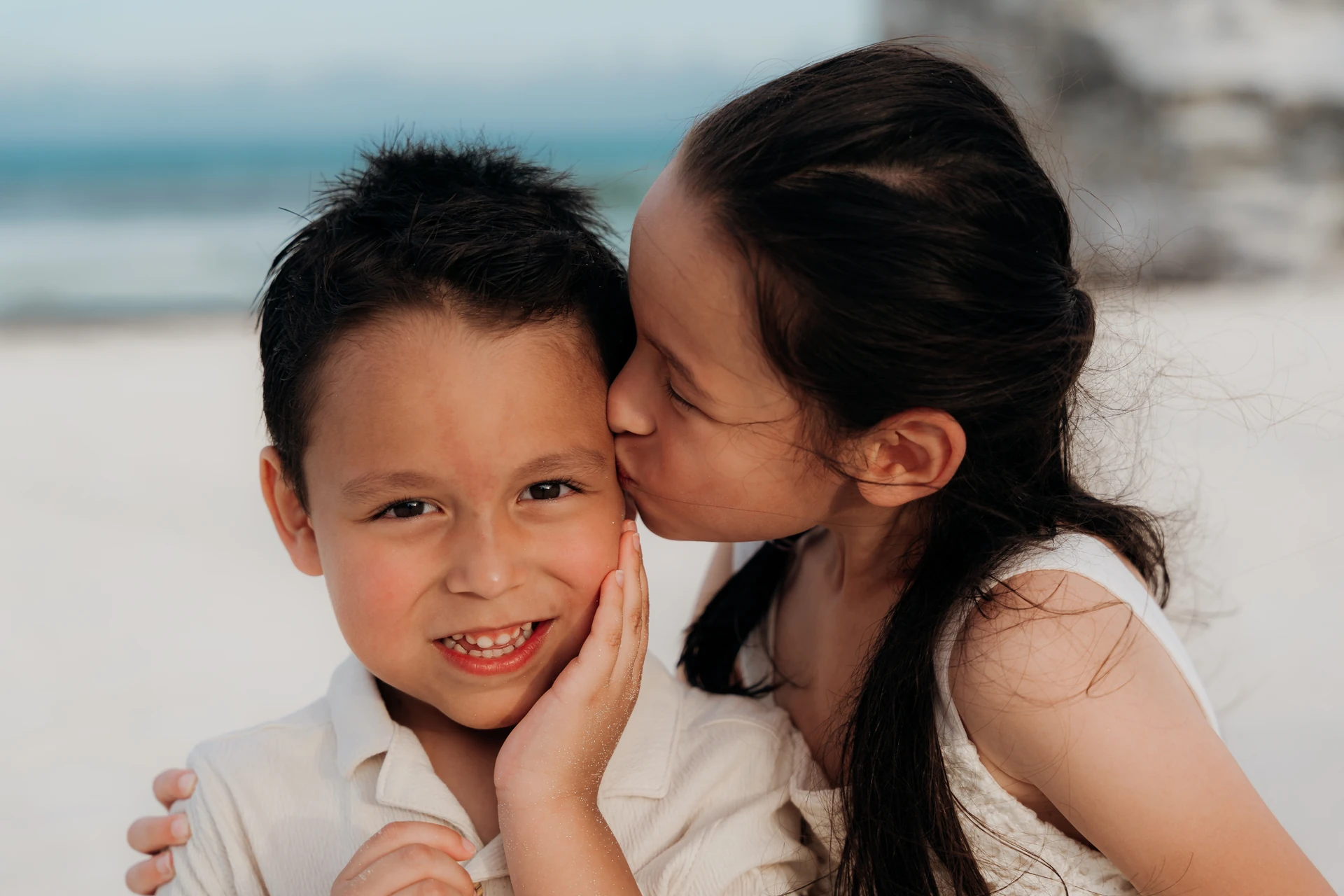 Sister kissing her little brother on the cheek in Isla Mujeres