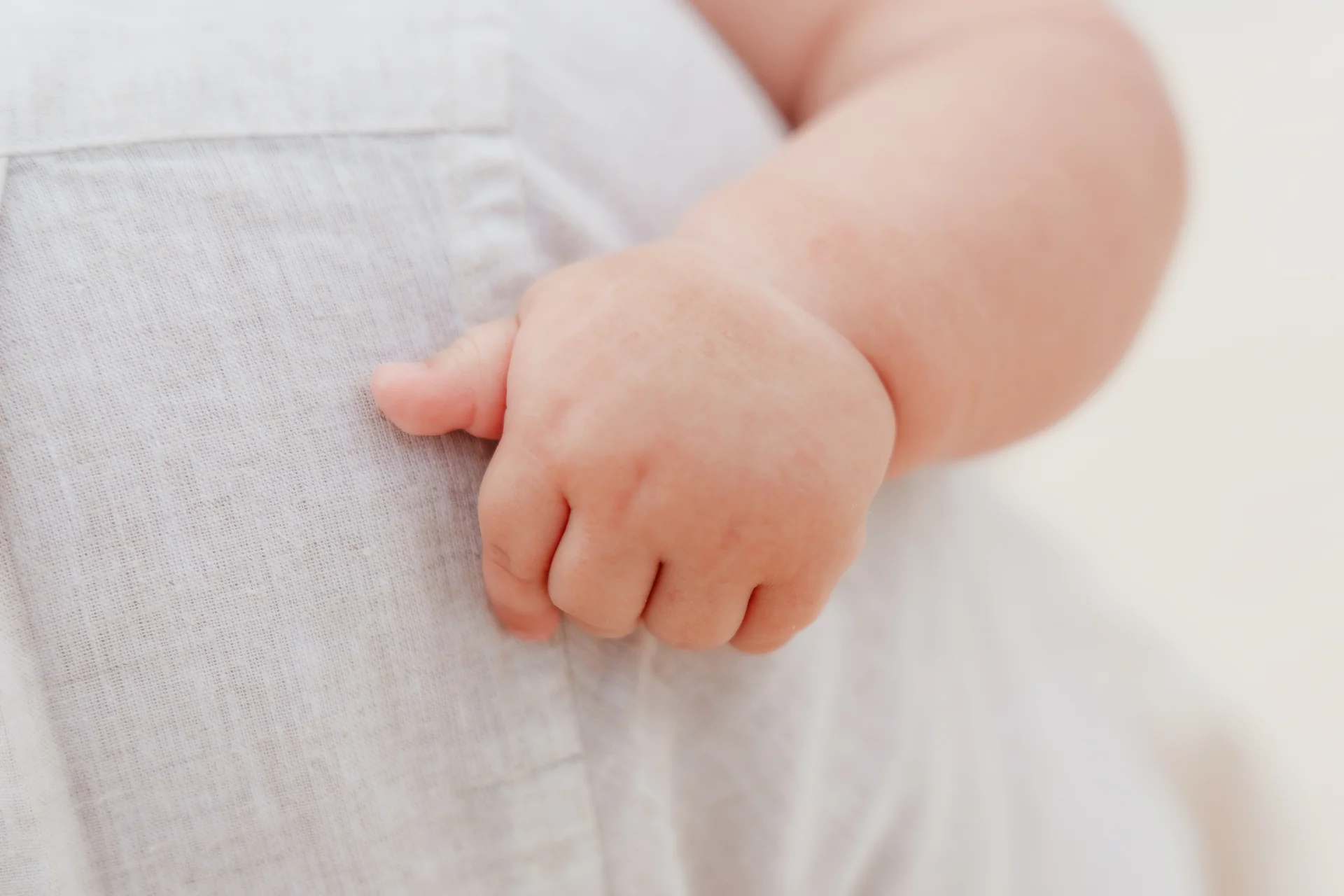Detail of the baby's hand resting on a parent's shirt, Playa Delfines, Cancún