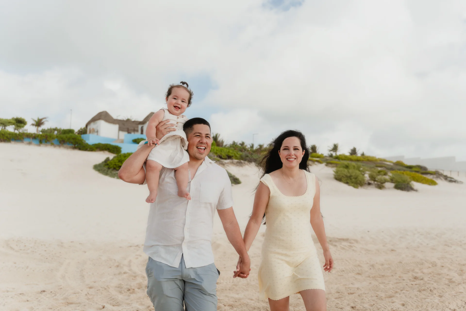 Family sharing a group hug on the sand, Playa Delfines, Cancún