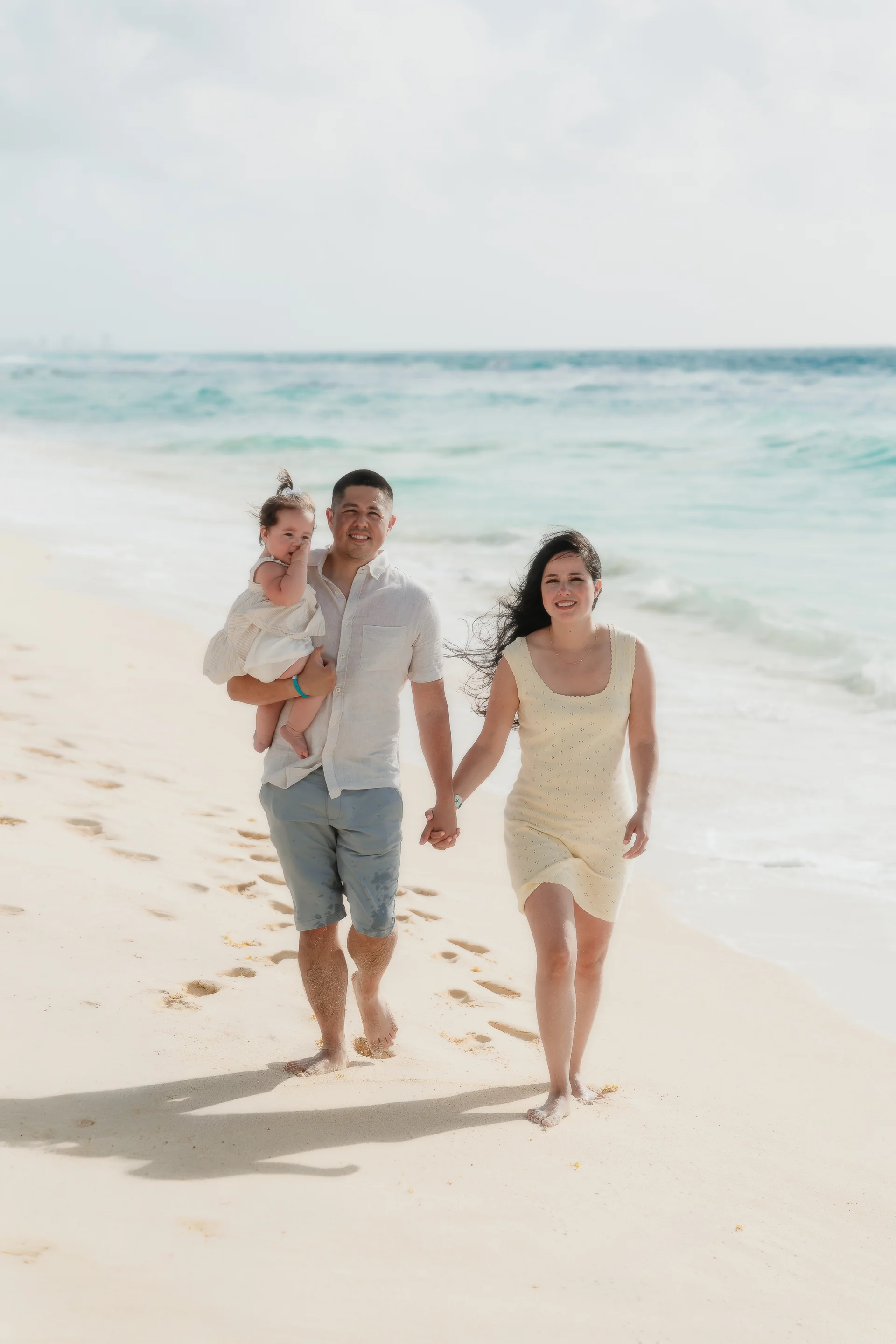 Mother and father framing their child between them, Playa Delfines, Cancún
