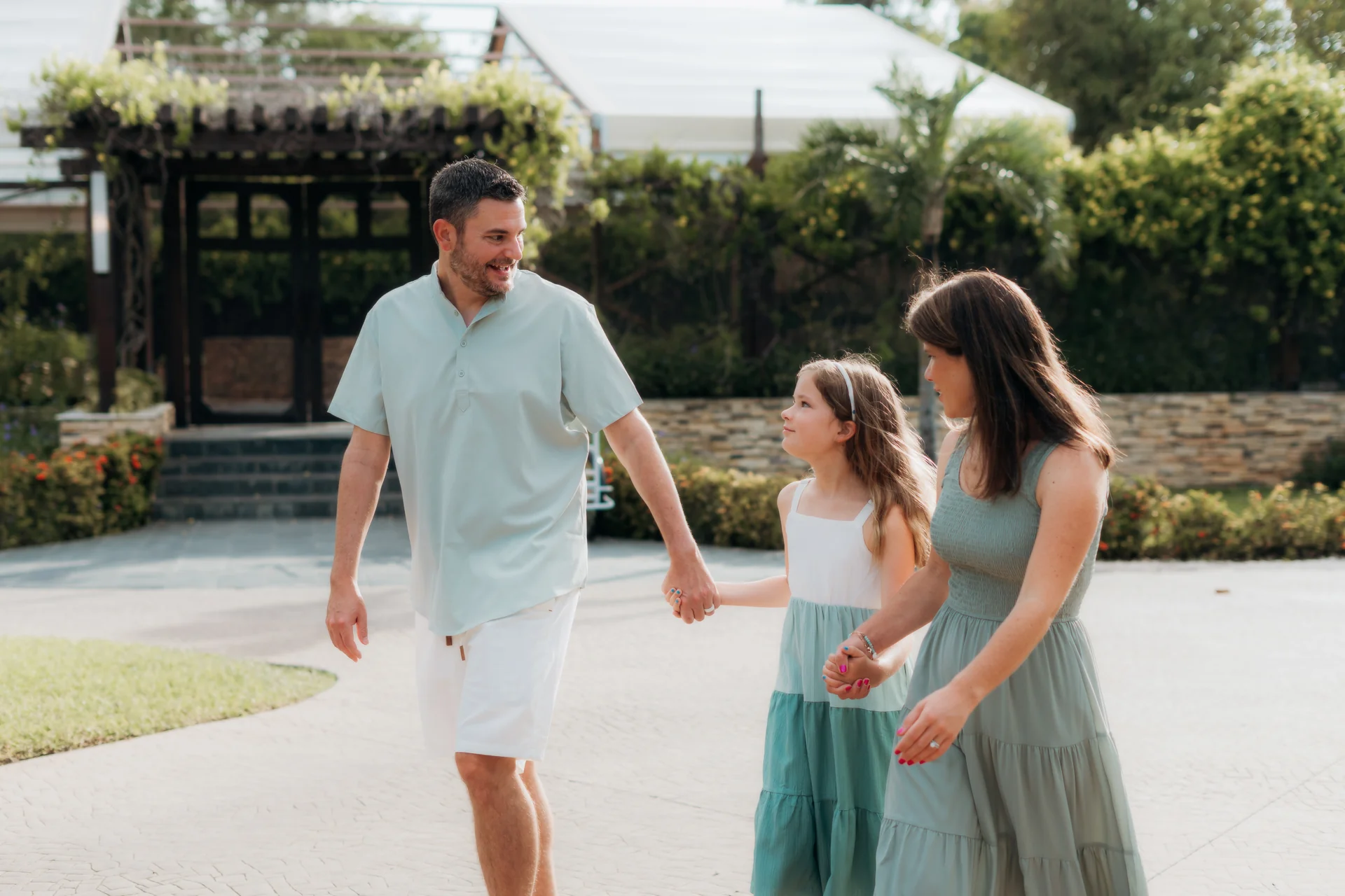 Father, daughter and mother holding hands and walking through the resort gardens, Rosewood Mayakoba, Riviera Maya