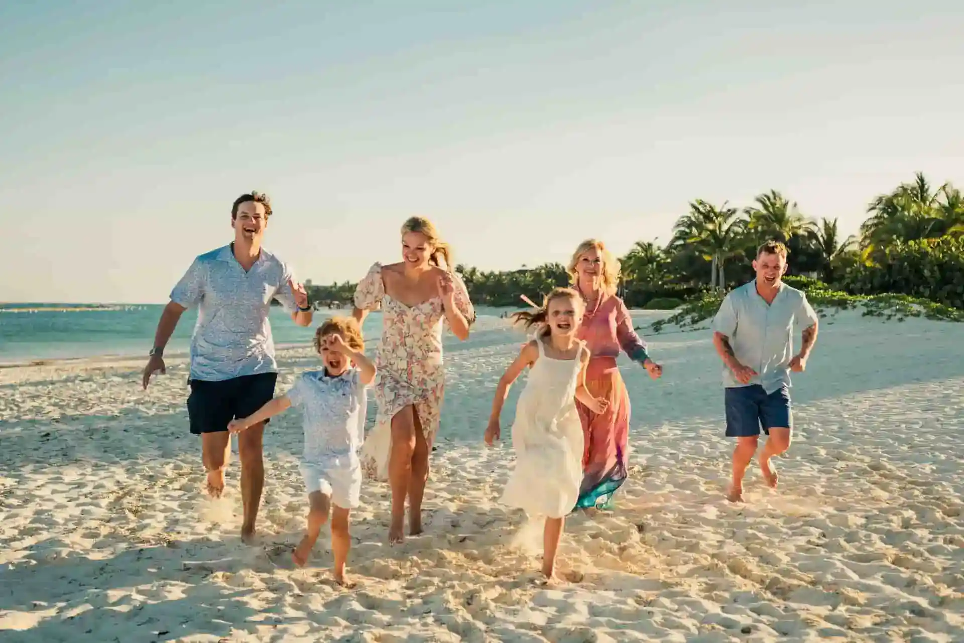 Family running together on the beach at golden hour in the Riviera Maya