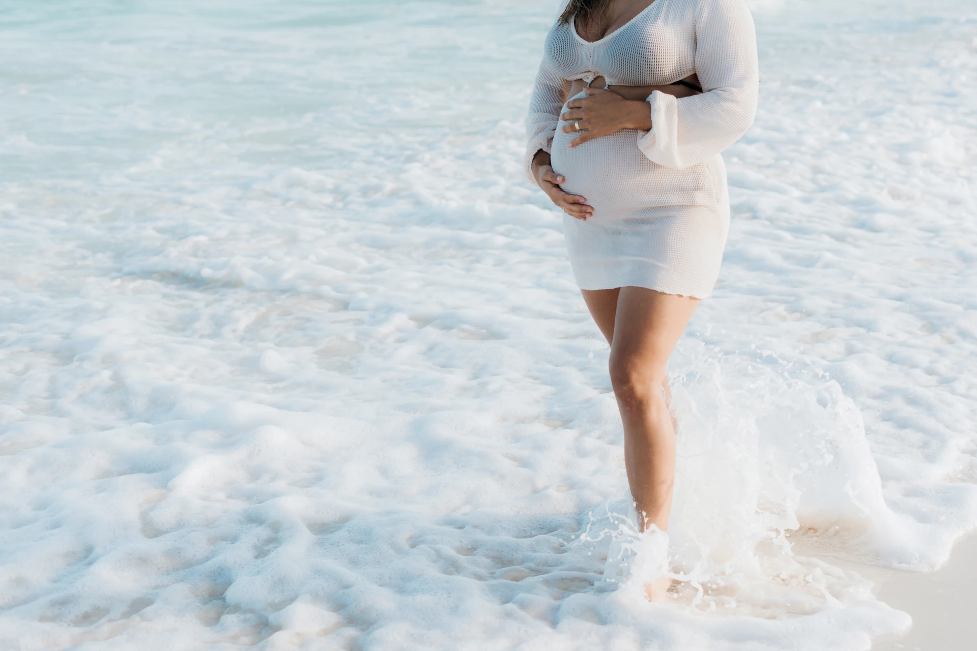 Expecting mother standing in the surf in the Riviera Maya