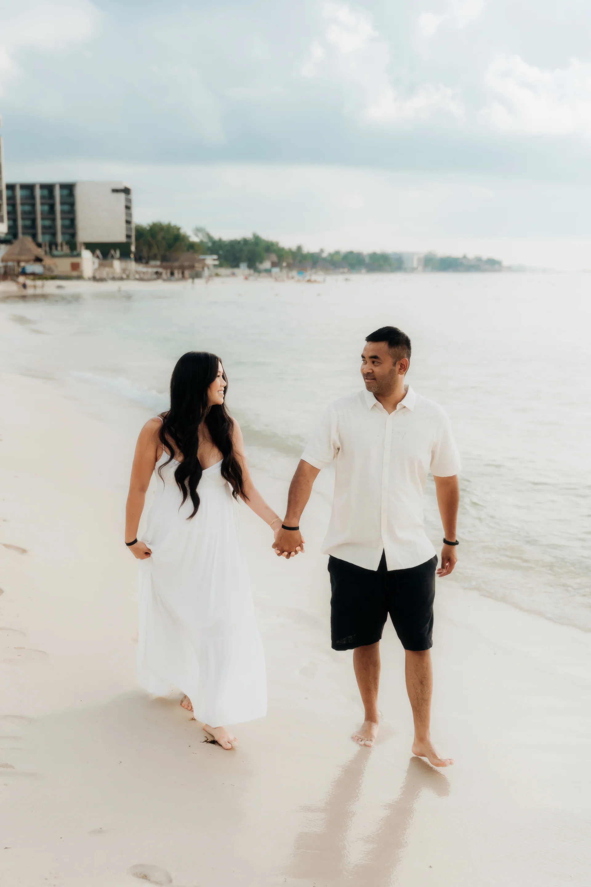 Couple holding hands and smiling at each other while walking the beach, Hyatt Vivid, Playa del Carmen
