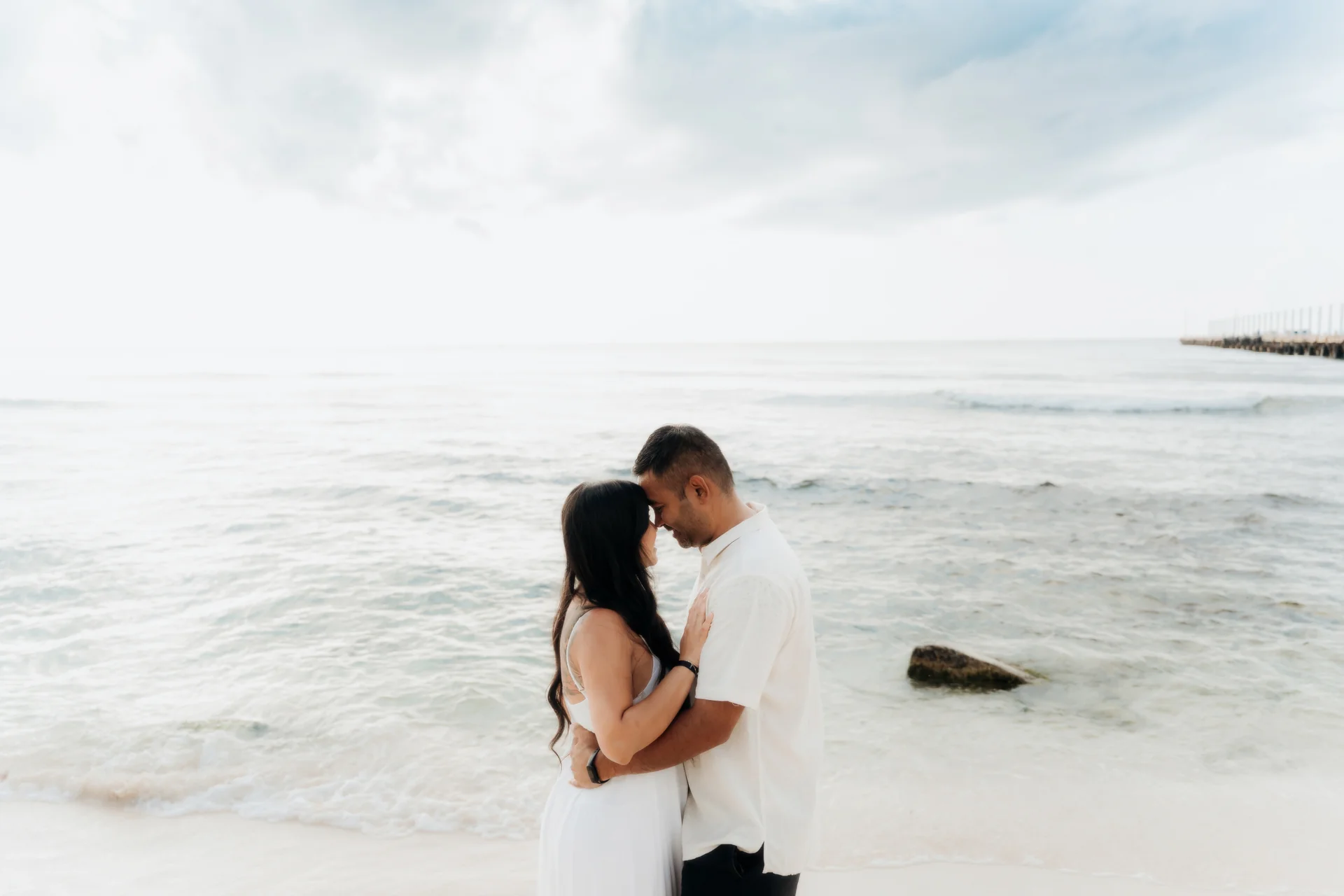 Couple standing forehead to forehead in an embrace at the water's edge, Hyatt Vivid, Playa del Carmen