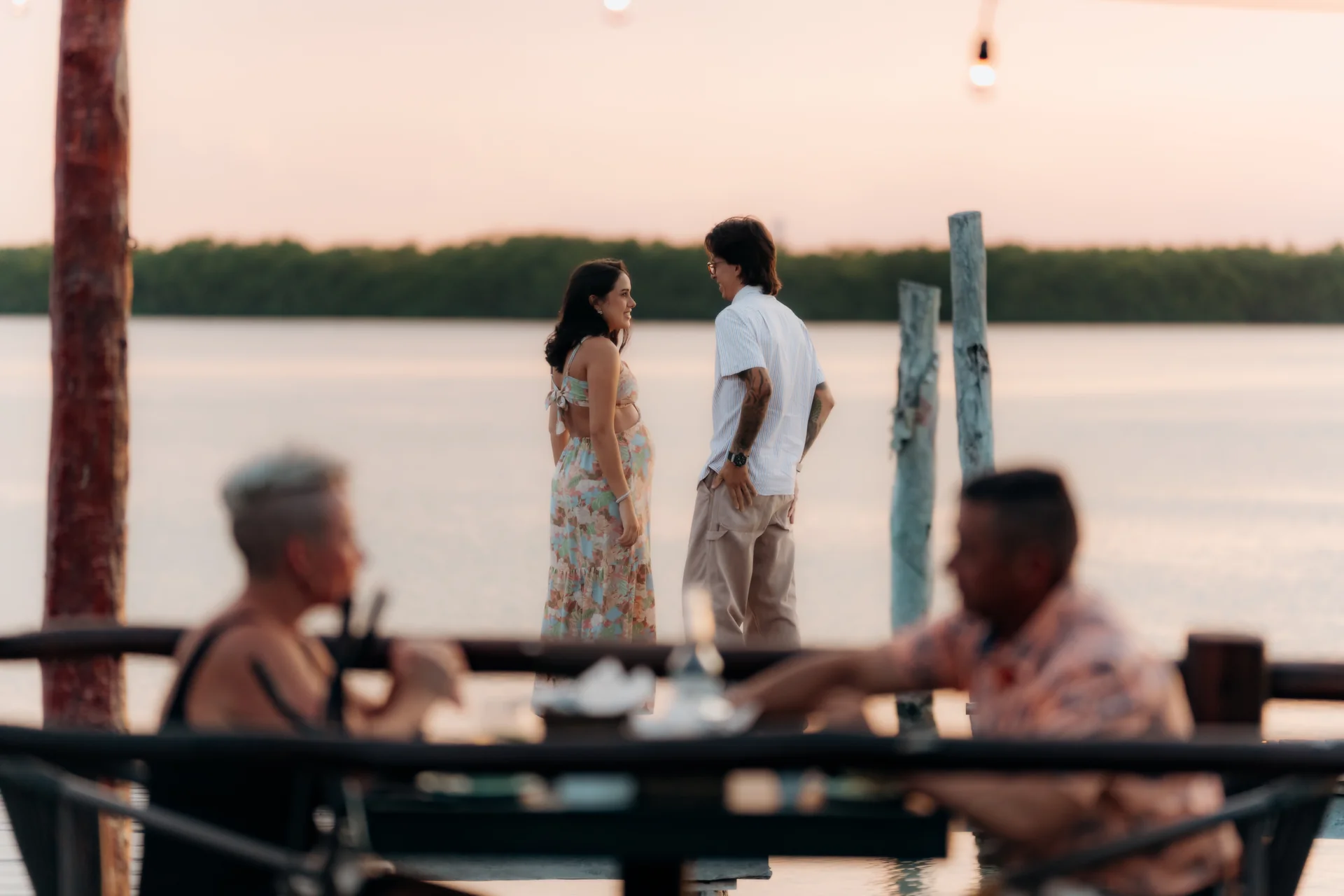 Expecting couple standing together on the dock at sunset over the lagoon, Navios restaurant, Cancún