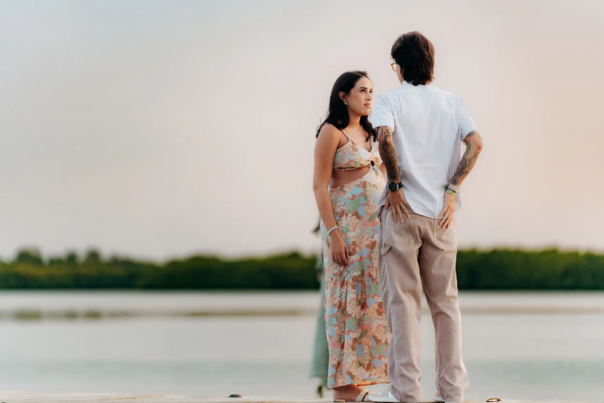 Expecting couple standing close together on the dock over the lagoon at dusk, Navios restaurant, Cancún
