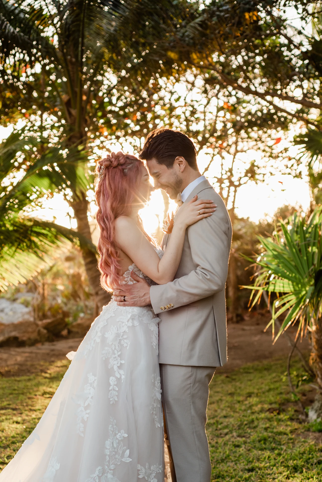 Bride and groom embracing at sunset with golden light flaring between them