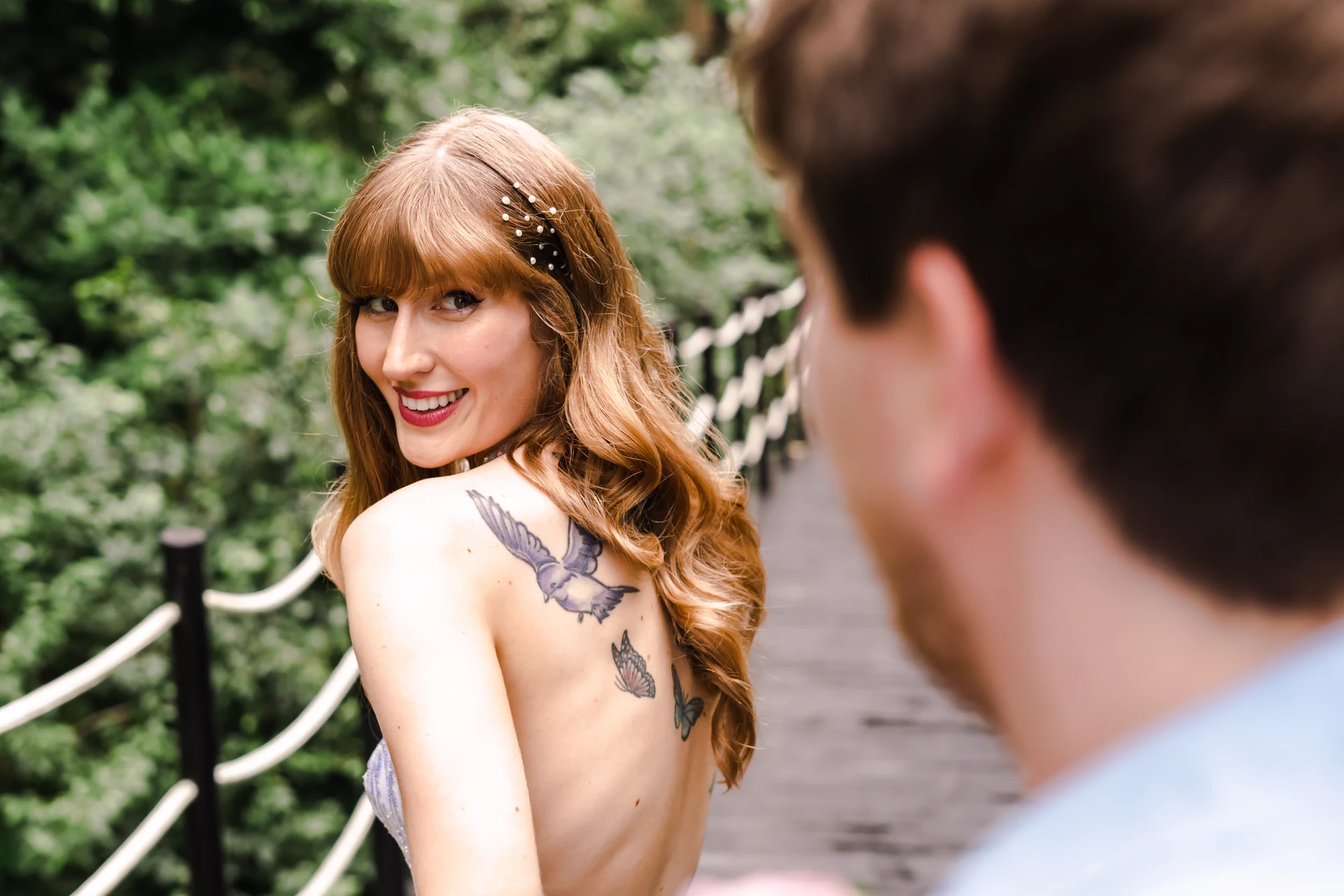 Bride looking back over her shoulder and smiling at the groom on a wooden jungle bridge